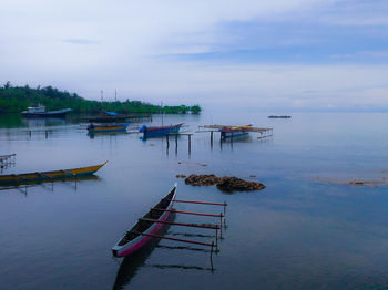 Fishing boats moored in lake against sky