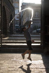 Side view of teenage boy walking on street against buildings