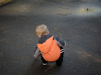 Rear view of boy crouching on street