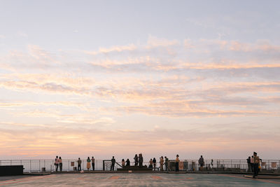 Silhouette people standing on beach against sky during sunset