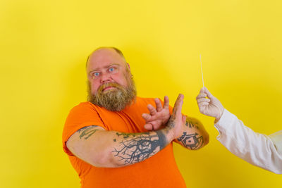 Portrait of man holding yellow camera