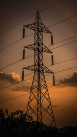 Low angle view of silhouette electricity pylon against sky during sunset
