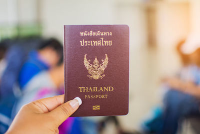 Close-up of woman hand holding passport at airport