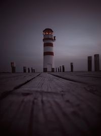 Low angle view of lighthouse by building against sky