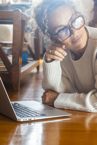 Portrait of woman using mobile phone while sitting on table