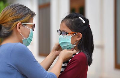 Mother wearing flu mask to daughter outdoors