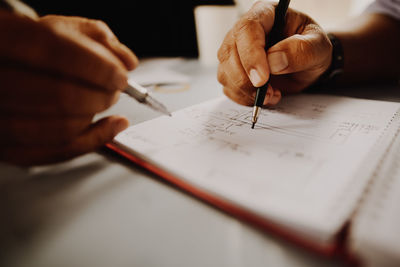 Close-up of hand holding pens over book