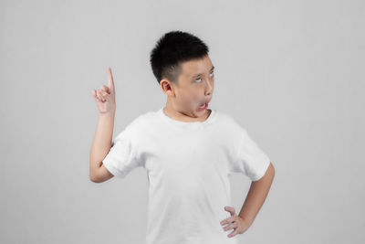 Boy looking away while standing against white background