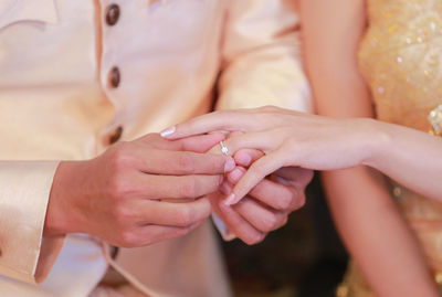 Midsection of wedding couple exchanging finger rings during ceremony