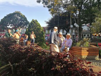 Group of people by plants against trees