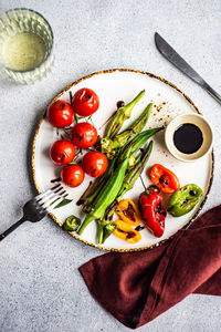 Healthy dinner with bbq bamia, paprika peppers and cherry tomatoes with soy and balzamico sauces served with glass of cold dry wine