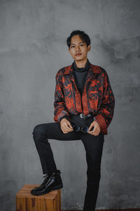 Portrait of young man standing against wall