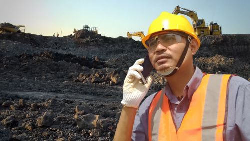 Portrait of man holding camera at construction site