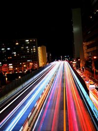 High angle view of light trails on street amidst buildings at night