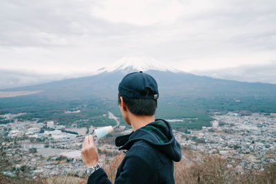 Rear view of man looking at cityscape against sky