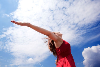 Rear view of woman with arms raised against sky