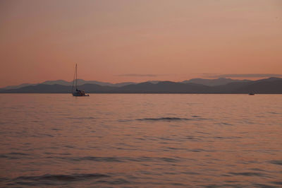 Silhouette boats in calm sea at sunset