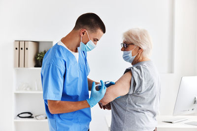 Nurse wearing mask vaccinating patient at clinic