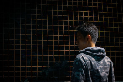 Rear view of man looking against brick wall