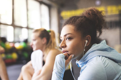 Young woman with earbuds having a break in gym