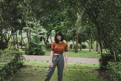 Portrait of young woman smiling while standing at park