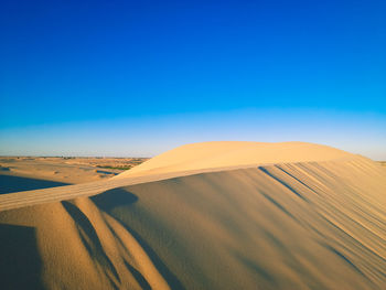 Scenic view of desert against clear blue sky