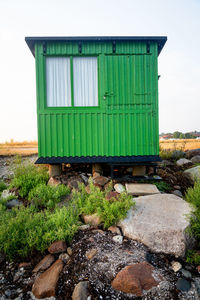 Green hut on rock against sky