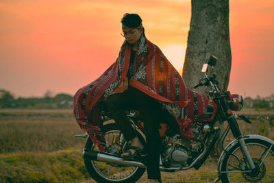 Full length of man sitting on motorcycle during sunset
