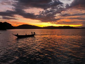 Silhouette people on boat in sea against sky during sunset