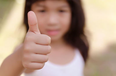 Girl gesturing thumbs up outdoors