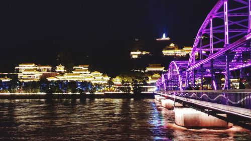 Illuminated bridge over river at night