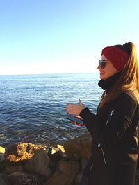 Woman standing by sea against clear sky