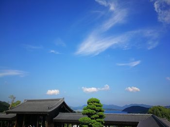 Houses by building against blue sky