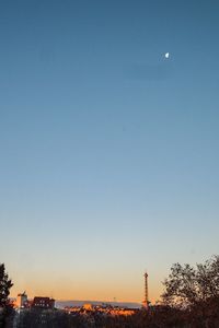 Scenic view of illuminated city against clear sky at dusk