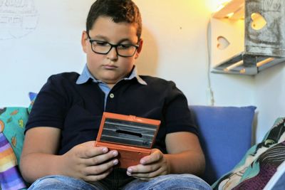 Midsection of boy holding mobile game