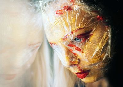 Close-up of woman looking away with plastic and paint on face