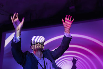 Male entrepreneur wearing vr glasses against projection screen in exhibition center