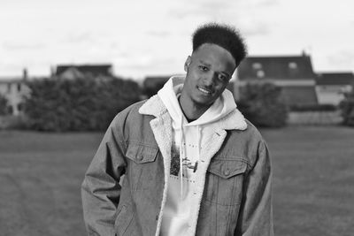 Portrait of smiling young man standing on land against sky