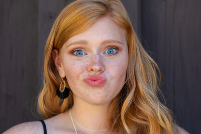 Portrait of teenage girl puckering lips against wall