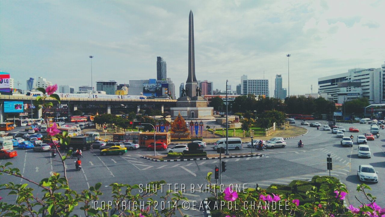 building exterior, architecture, city, car, built structure, transportation, land vehicle, mode of transport, sky, street, city life, road, city street, cityscape, traffic, incidental people, skyscraper, cloud - sky, building, street light