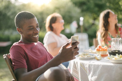 Boy smiling while using mobile phone in backyard during garden party