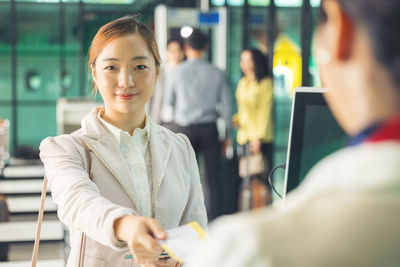 At the airport check-in counter, a passenger hands over his documents to the manager via a counter 