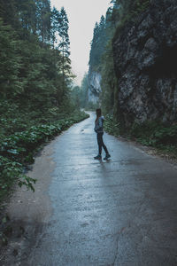 Rear view of man walking on road amidst trees