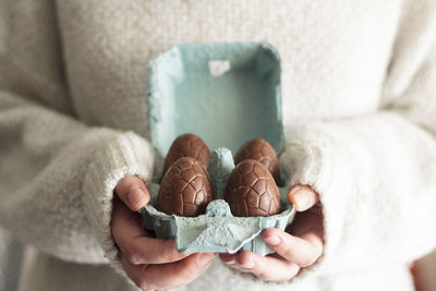 Close up of woman holding carton egg box with easter chocolate eggs