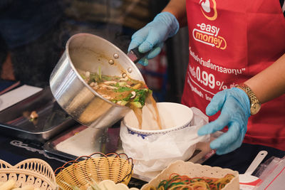 Midsection of woman putting food in bowl