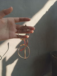 High angle view of hand holding eyeglasses against wall