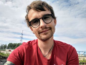 Portrait of young man with eyeglasses against sky