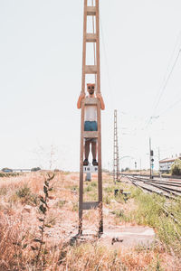 Portrait of mid adult man standing on pole against clear sky