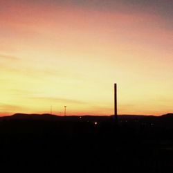 Silhouette of factory against sky during sunset