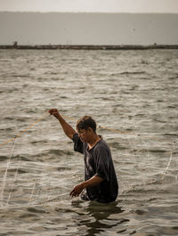 Side view of fisherman with fishing net standing in sea
